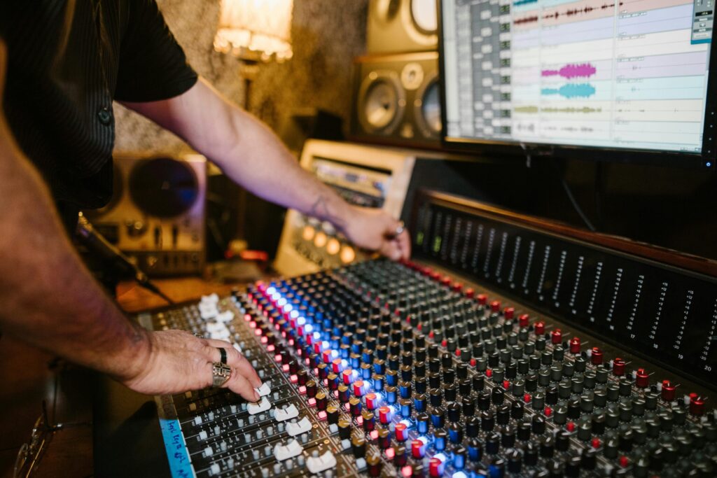Close-up of a sound engineer using an audio mixer in a modern recording studio setting.